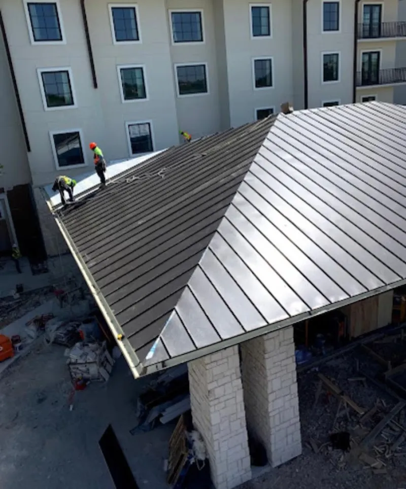 Crew installing standing seam metal roof panels on a commercial project in Genesee